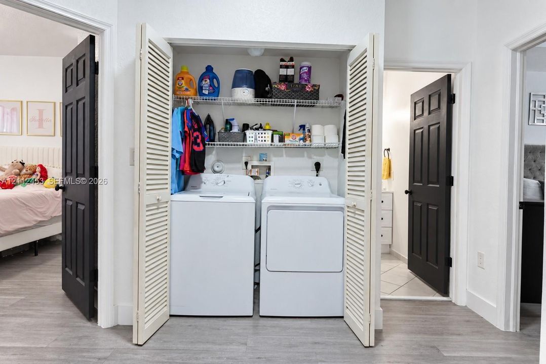 Laundry closet featuring bifold louvered doors, built-in wire shelving, and wood-finish flooring