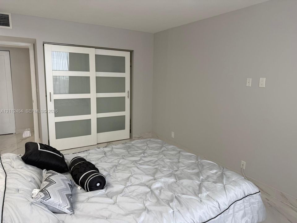 Sliding closet doors featuring frosted glass panels and white frames, stone-finish flooring, and neutral wall tones