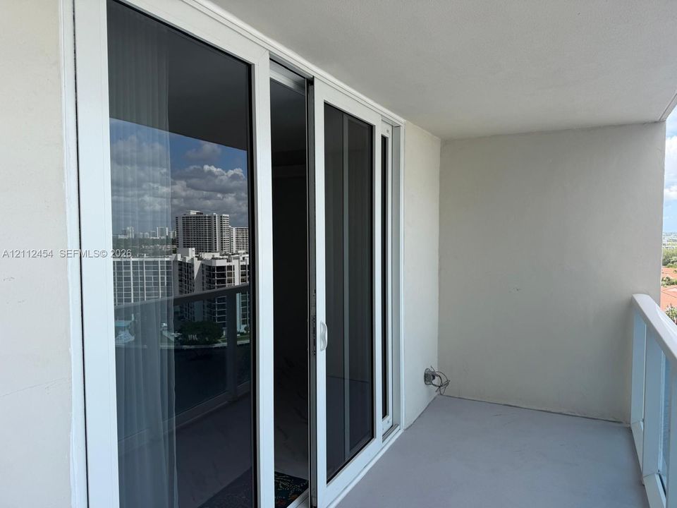 Private balcony featuring glass-panel railings and white-frame sliding glass doors