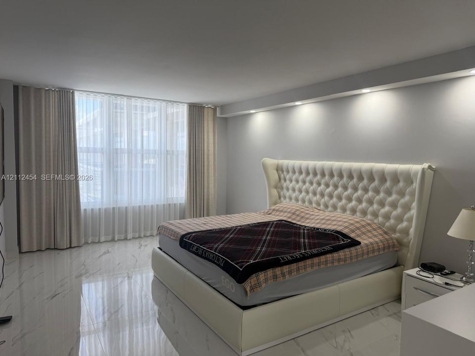 Large-format tile flooring with a neutral veined finish, floor-to-ceiling windows, and recessed ceiling lighting