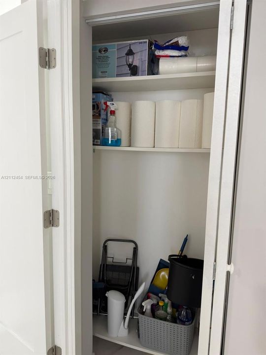 Storage closet featuring white interior walls, white shelving, and white bifold doors with brushed nickel hinges