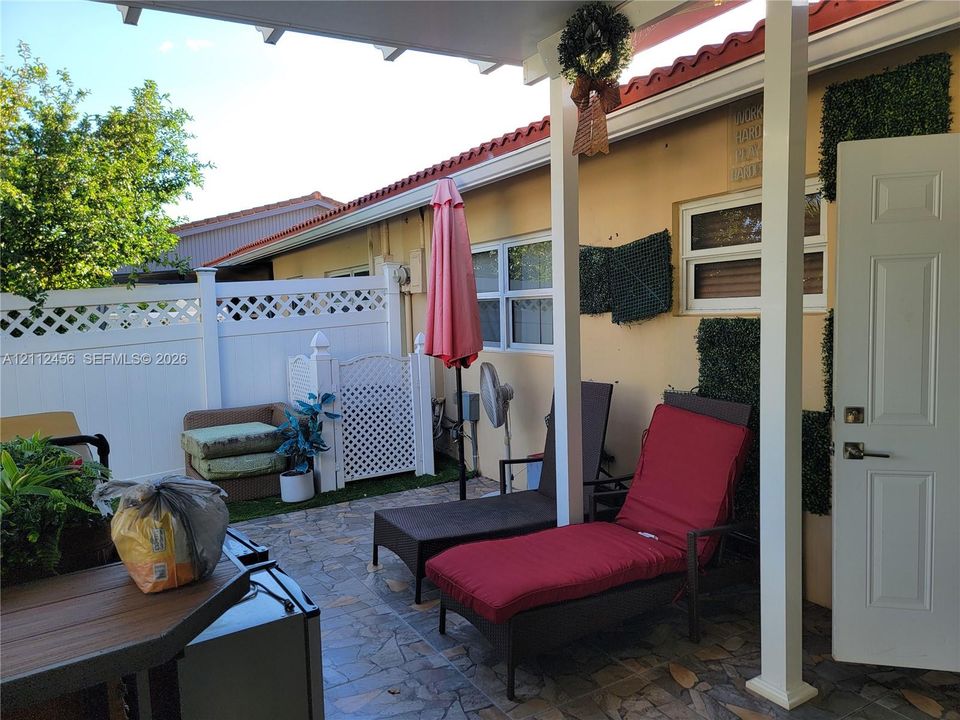 Private backyard featuring a manicured lawn, white vinyl fencing with lattice detailing, and a detached pergola