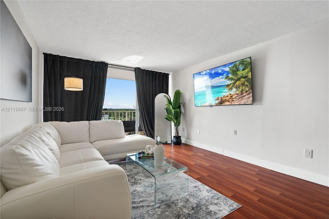 Living area featuring wood-finish flooring, textured ceiling, and access to an outdoor balcony