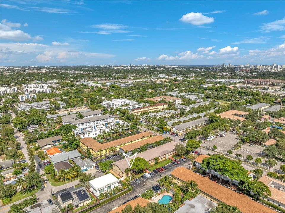 Aerial perspective of a multi-unit property featuring dedicated surface parking, mature landscaping, and proximity to regional infrastructure