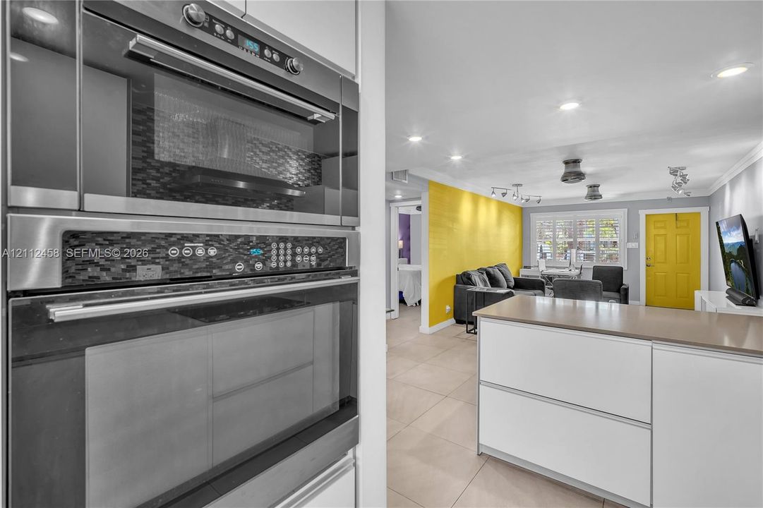 Built-in stainless steel microwave and oven combination, tiled flooring, recessed lighting, and kitchen island with a solid-surface countertop