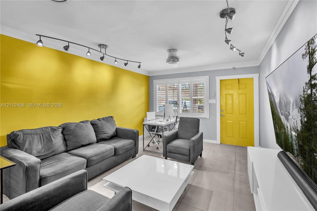 Interior space featuring large-format tile flooring, multi-directional track lighting, and window shutters