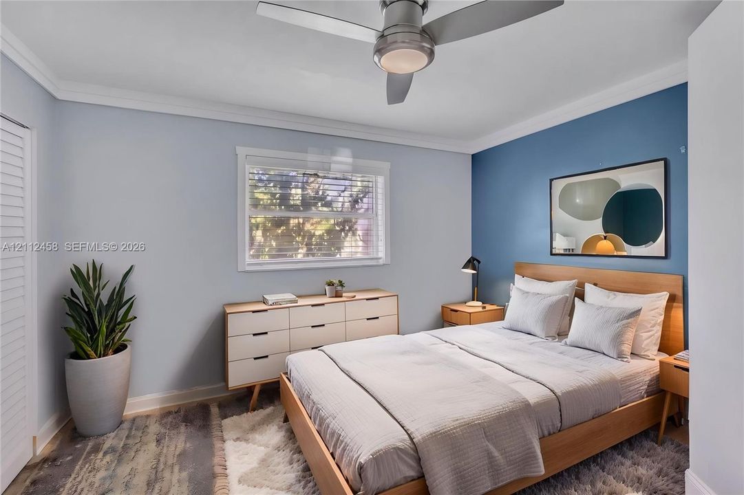 Bedroom featuring crown molding, a multi-pane window, and a ceiling fan with integrated lighting