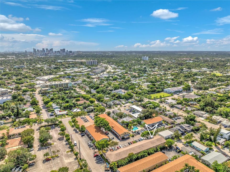 Aerial perspective featuring low-rise multi-unit buildings with pitched roofs, integrated parking, and palm-lined grounds