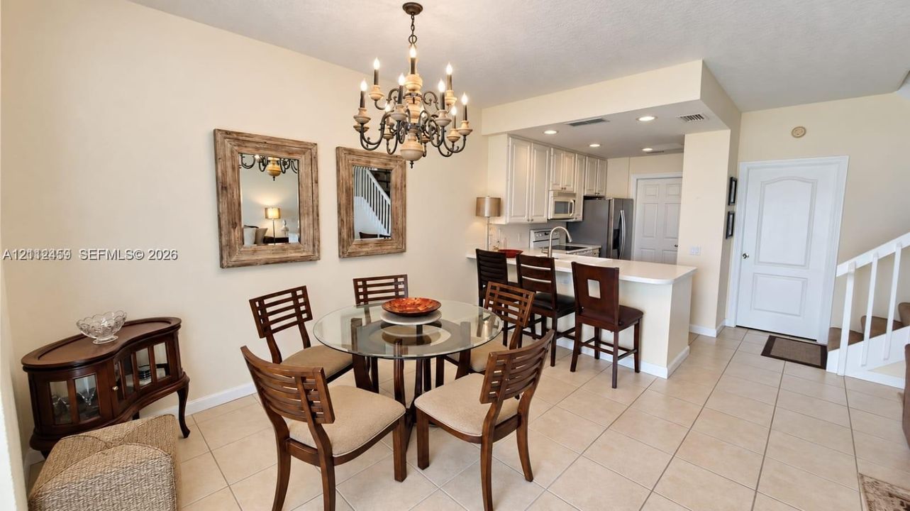 Open-concept kitchen featuring white shaker-style cabinetry, stainless steel appliances, and a solid-surface breakfast bar