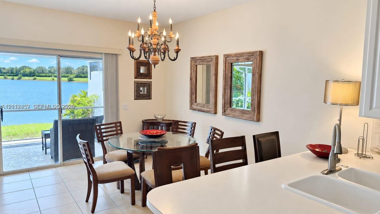 Dining area featuring tile flooring, a multi-light chandelier, and sliding glass doors with water scenery