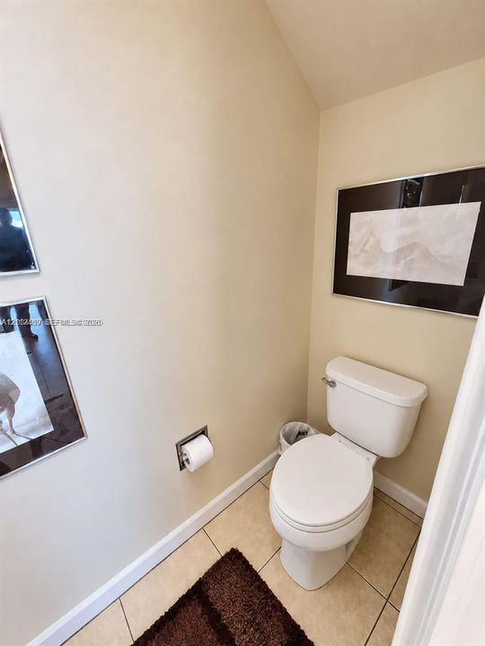 Neutral-toned walls, floor-mounted toilet, and ceramic tile flooring featuring a recessed toilet paper holder