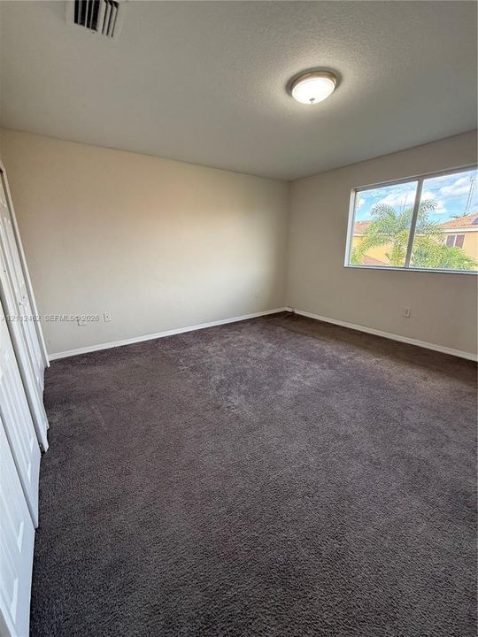 Interior space featuring neutral wall tones, wall-to-wall carpeting, a large sliding-door closet, and a single-pane window
