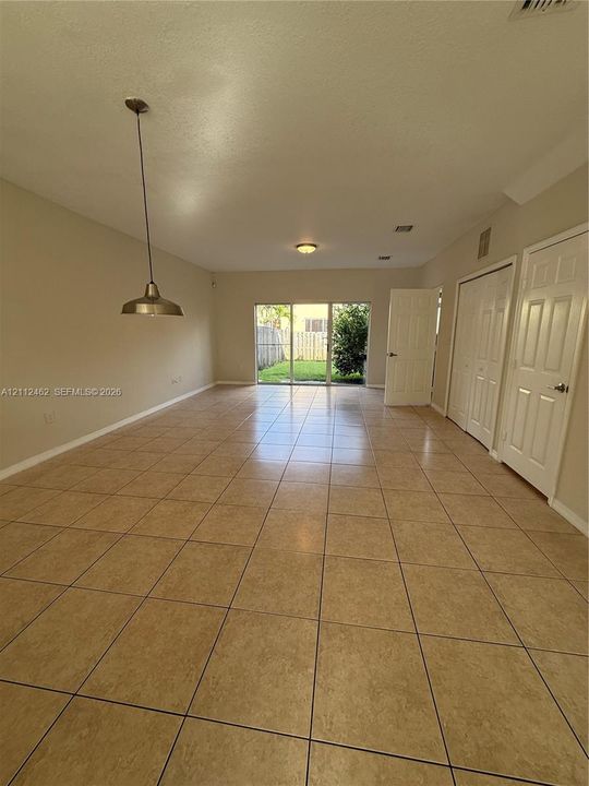 Interior space featuring neutral wall paint, large format ceramic tile flooring, a metal pendant light fixture, sliding glass doors, and interior paneled doors