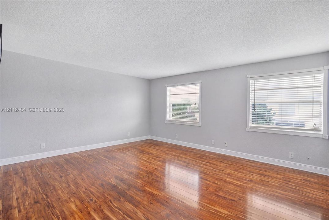 Interior space featuring wood-finish flooring, light-toned wall finishes, two dual-pane windows, and horizontal window blinds