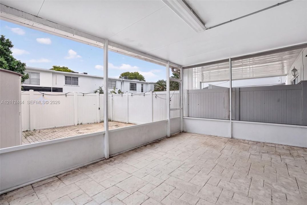 Screened-in patio featuring a solid roof, stamped concrete flooring, and a private enclosed outdoor area with vinyl privacy fencing