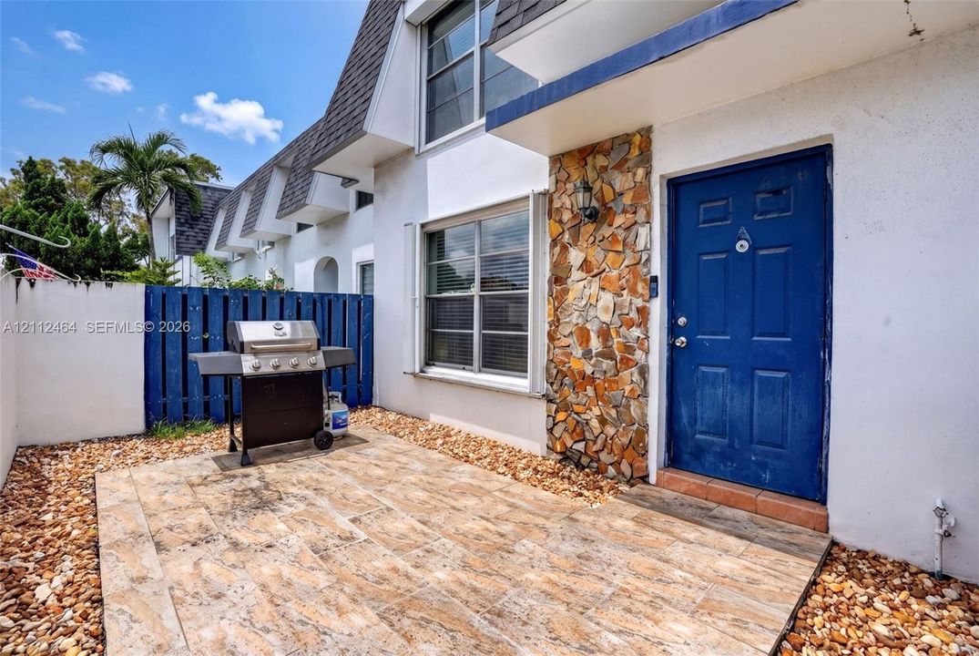 Private courtyard featuring tile hardscaping, decorative stone exterior accents, and perimeter fencing