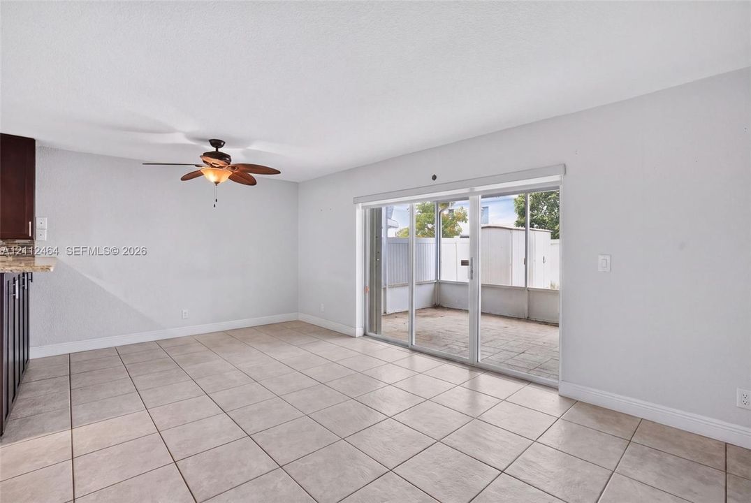Ceramic tile flooring, sliding glass patio doors, and ceiling fan with integrated lighting