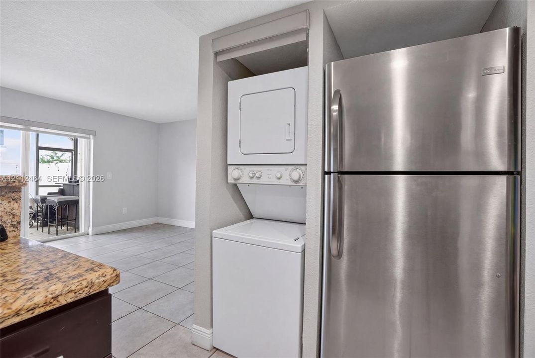 Stainless steel refrigerator, stacked laundry unit, and stone-surfaced countertop