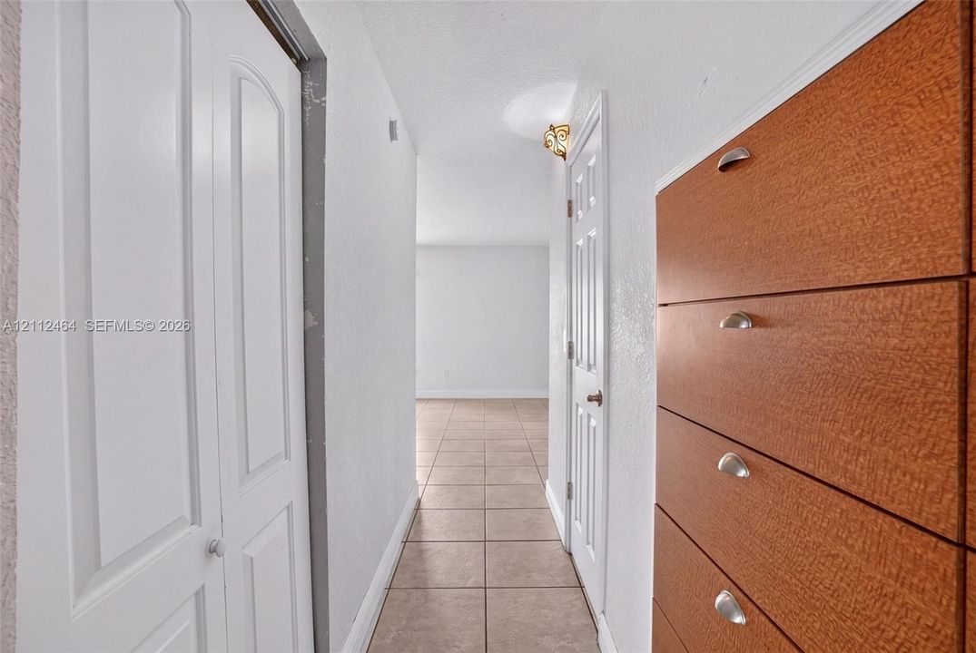 Hallway featuring ceramic tile flooring, built-in wooden cabinetry with metal hardware, and multi-panel interior doors