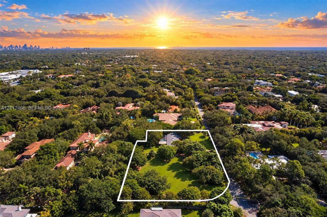 Aerial perspective of a sprawling parcel featuring expansive green lawns, established mature trees, and a distant horizon backdrop