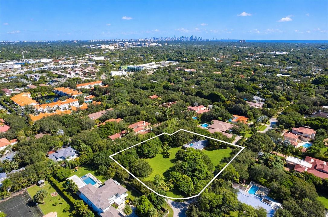 Aerial perspective of a sprawling property featuring expansive open grounds, mature canopy trees, and an integrated swimming pool