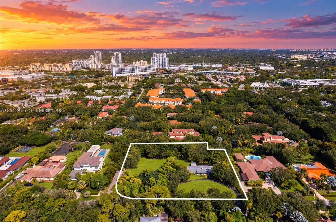 Aerial perspective of a sprawling property featuring mature canopy trees, expansive lawn areas, and a multi-section residence
