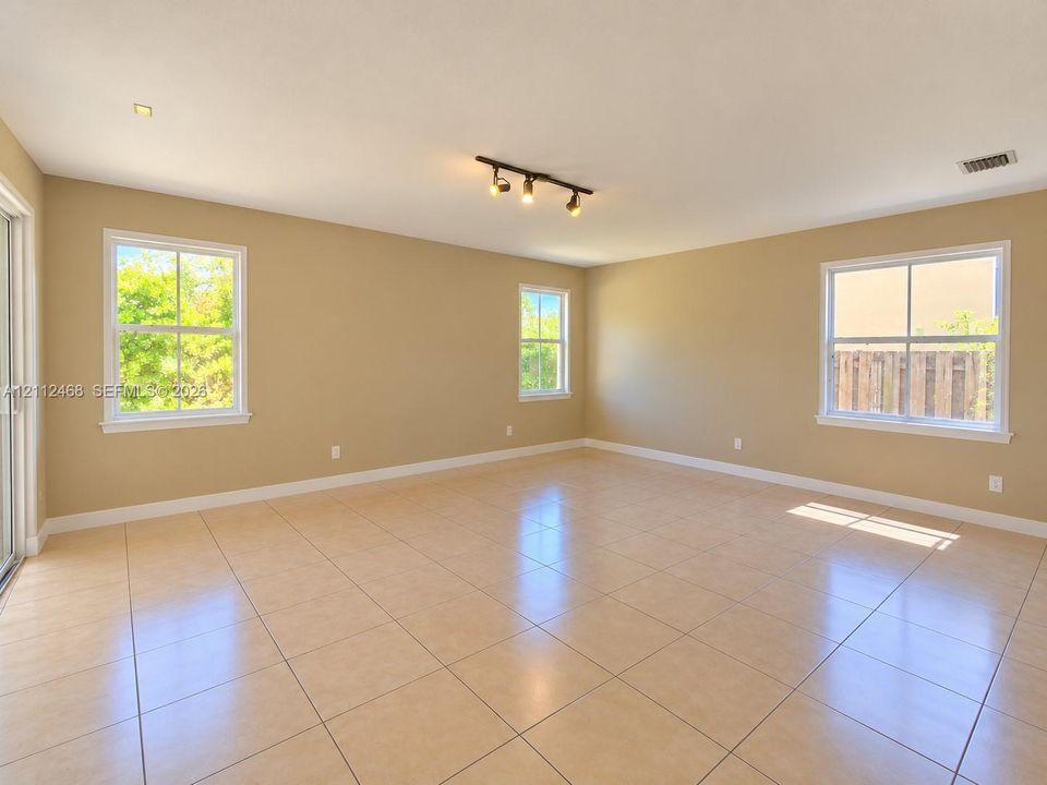 Neutral-toned interior featuring ceramic tile flooring, three multi-pane windows, and a ceiling-mounted track lighting fixture