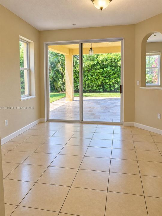 Tile flooring, sliding glass door, arched wall opening, and covered exterior patio with stone-finish pavers