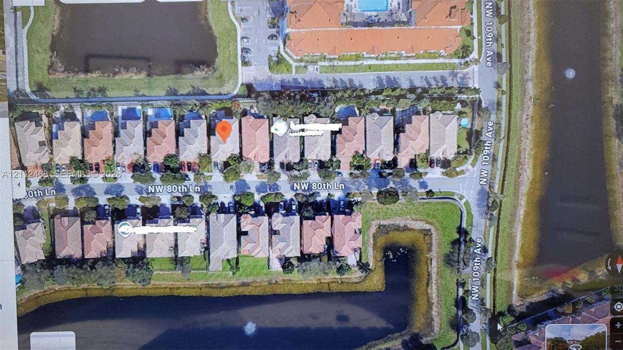 Aerial perspective of a residential lot situated along a water feature with expansive greenspace and paved street access