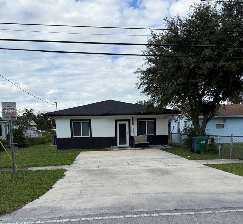 Single-story exterior featuring two-tone smooth stucco siding, a hipped roofline, and a concrete driveway