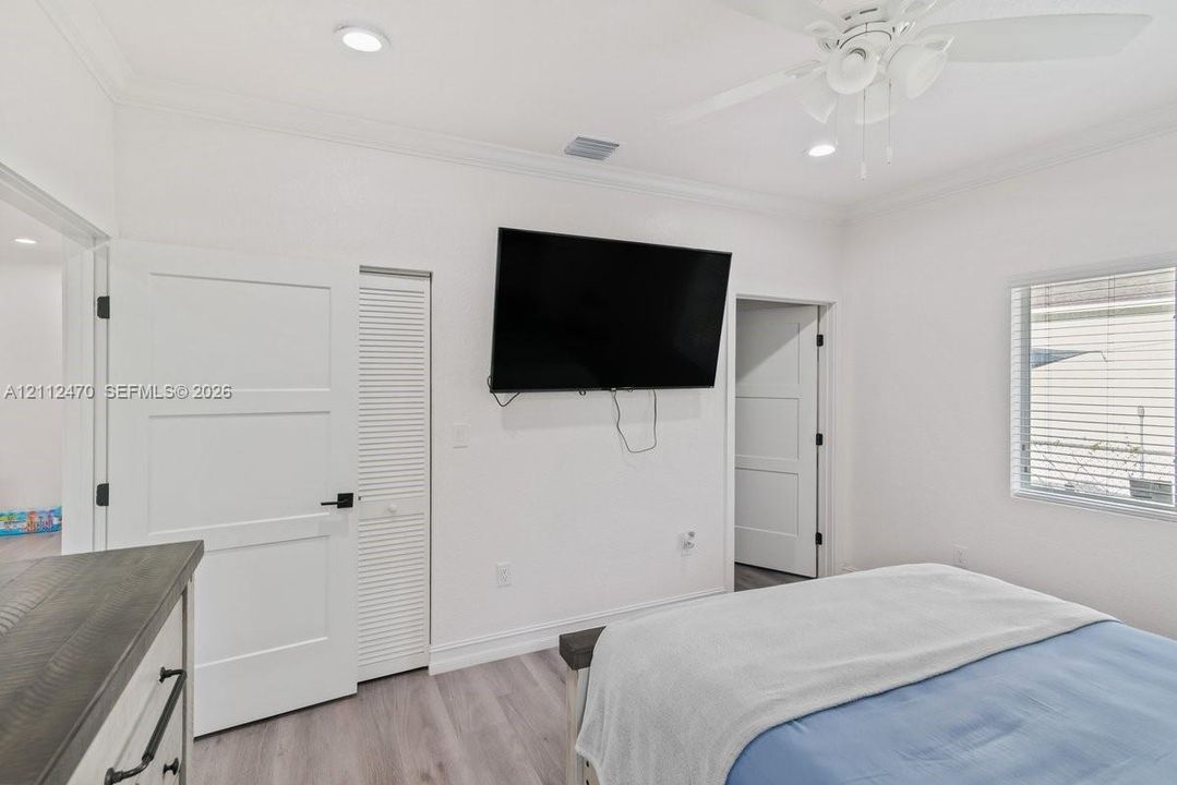 Room featuring recessed lighting, wood-finish flooring, crown molding, a ceiling fan, and louvered closet doors