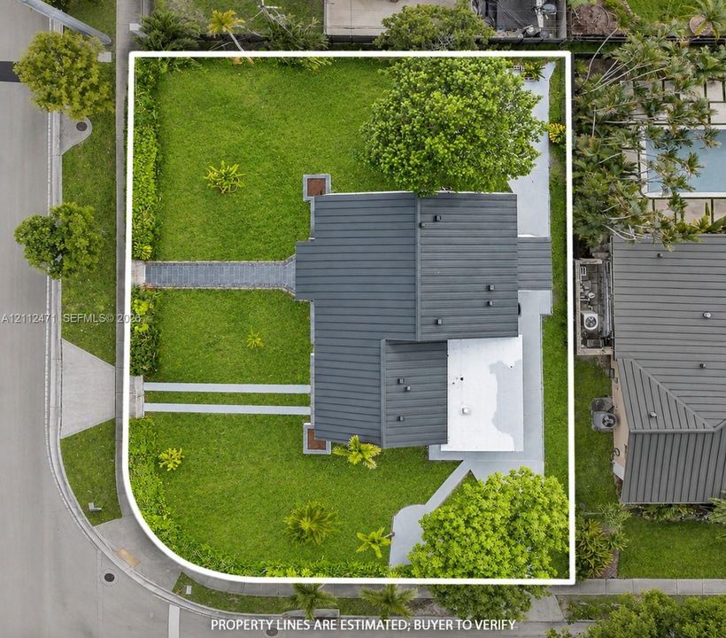Corner lot featuring extensive lawn space, mature perimeter landscaping, and dual paved walkways