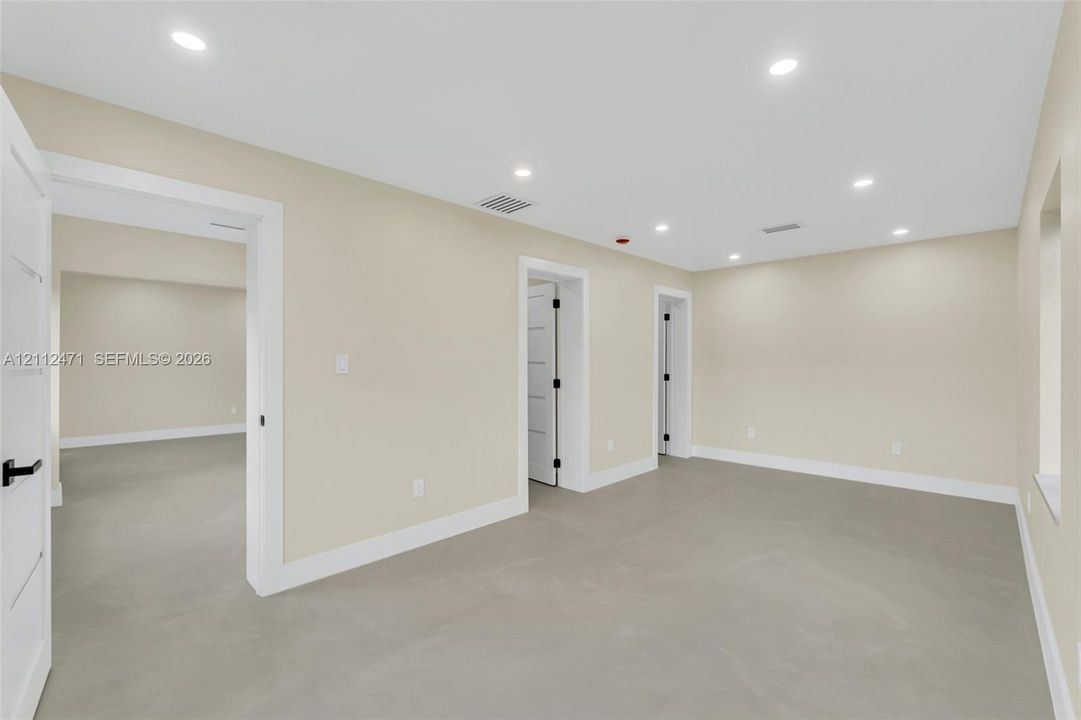 Interior room featuring recessed ceiling lighting, light-toned flooring, and multi-panel interior doors with matte black hardware