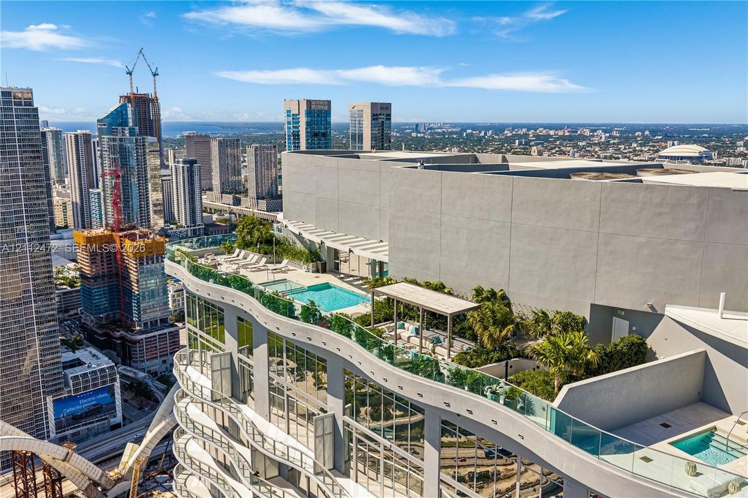 Rooftop terrace featuring a swimming pool, integrated landscaping, pergola-covered lounge area, and glass balcony railings