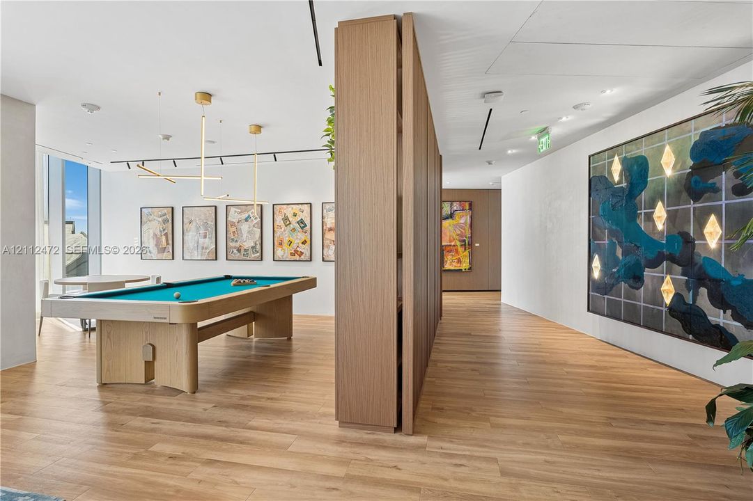 Wood-finish flooring, floor-to-ceiling wood-paneled room divider, linear pendant lighting, and floor-to-ceiling windows