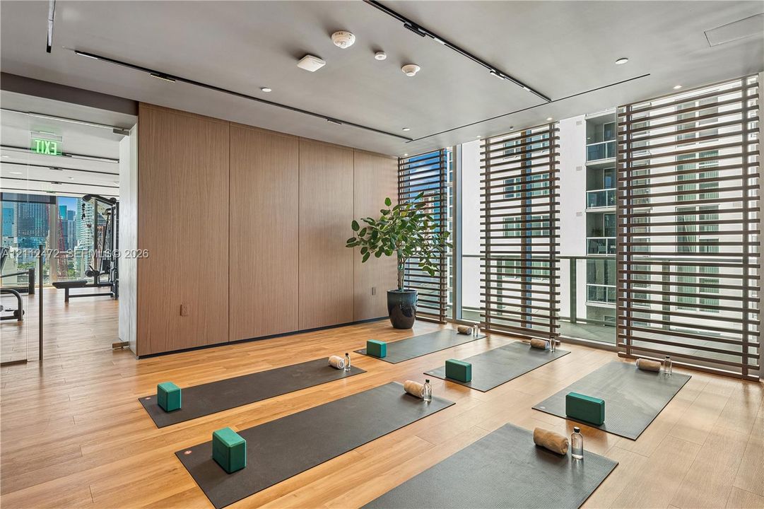 Studio space featuring wood-finish flooring, full-height wood paneling, track lighting, and vertical slatted privacy screening