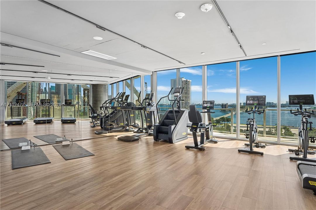 Fitness center featuring floor-to-ceiling windows, wood-finish flooring, recessed lighting, and mirrored walls