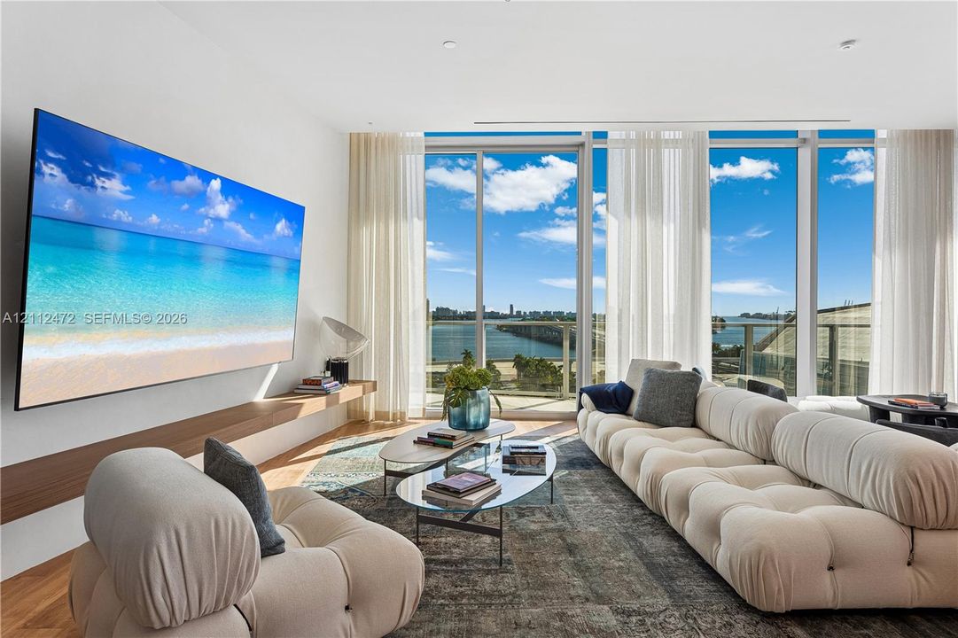 Floor-to-ceiling windows, wood-finish flooring, and a wall-mounted floating wood shelf