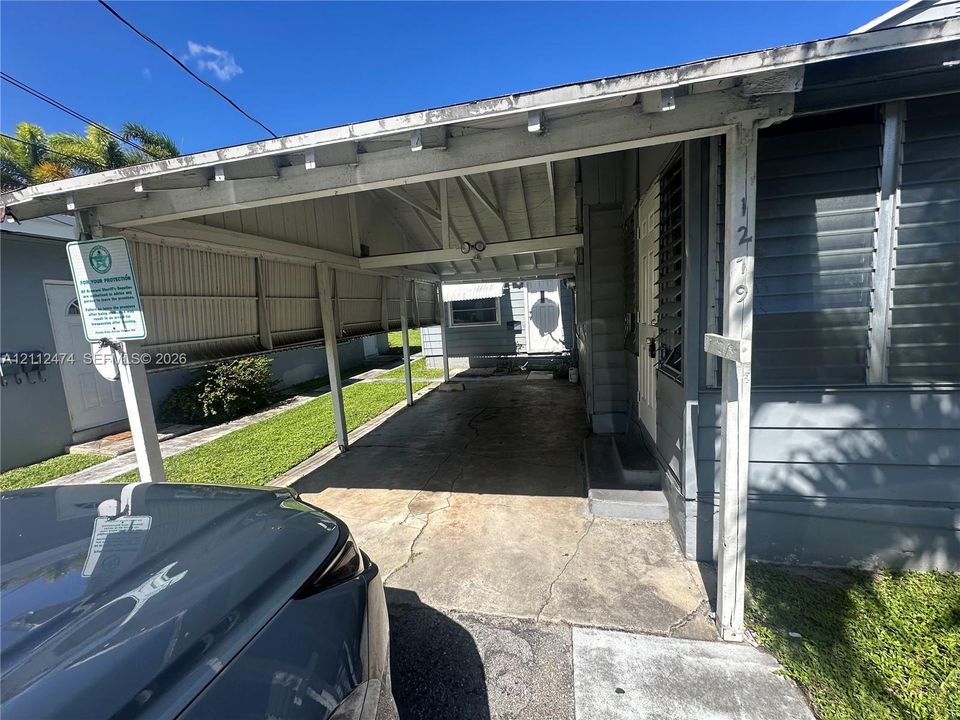Attached carport with concrete flooring, exposed beam ceiling structure, and metal siding
