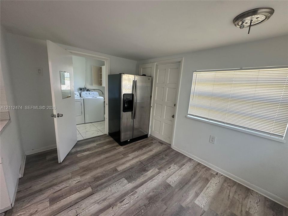 Wood-finish flooring, stainless steel side-by-side refrigerator, multi-panel entry door, and window with horizontal blinds