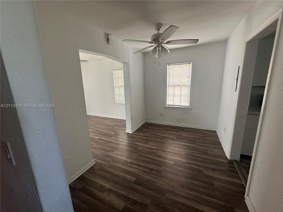 Interior space featuring wood-finish flooring, white walls, and a ceiling-mounted light fixture with a five-blade fan