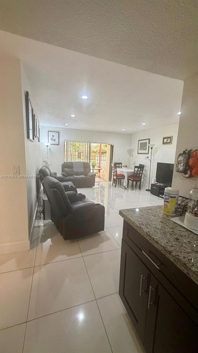 Open-concept interior featuring large-format tile flooring, recessed lighting, and a sliding glass door