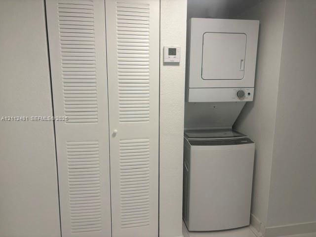 Stacked laundry unit featuring a top-load washer and front-load dryer paired with white bi-fold closet doors