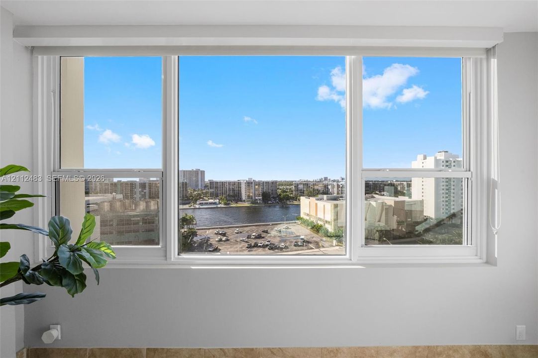 Large triple-pane window featuring white frames and a wide sill, showcasing expansive water and urban scenery