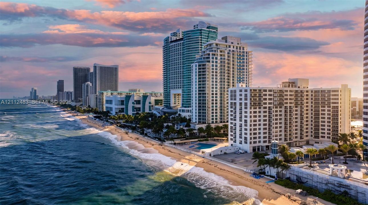 Coastal high-rise exterior featuring a direct oceanfront location, expansive shoreline, ground-level pool, and palm-lined landscaping