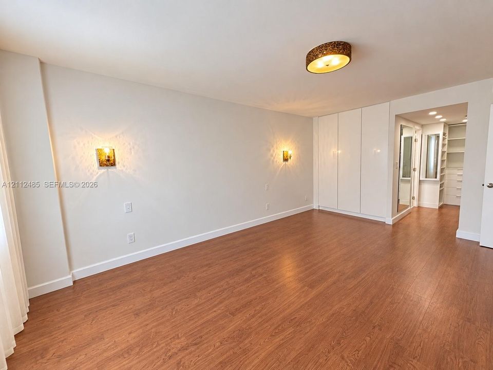 Wood-finish flooring, built-in floor-to-ceiling cabinetry, recessed lighting, and wall-mounted sconces