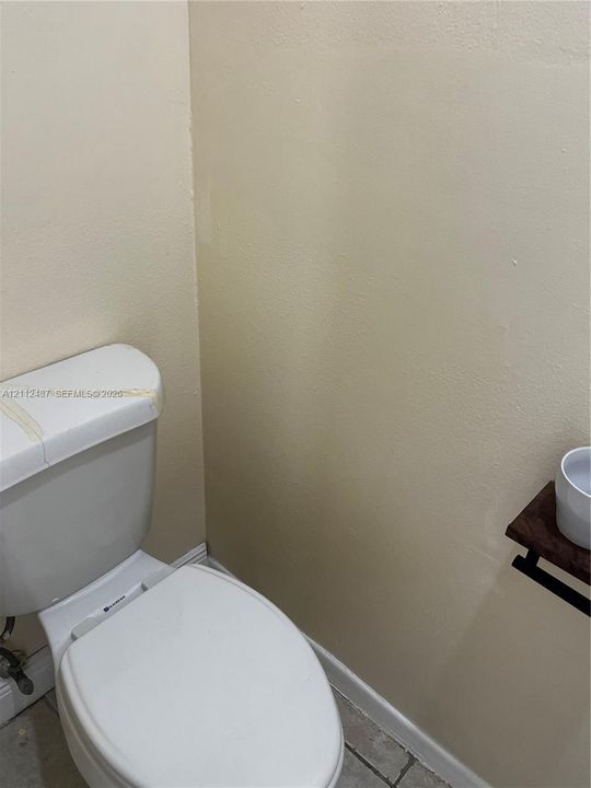 White porcelain toilet and wall-mounted wooden shelf fixture