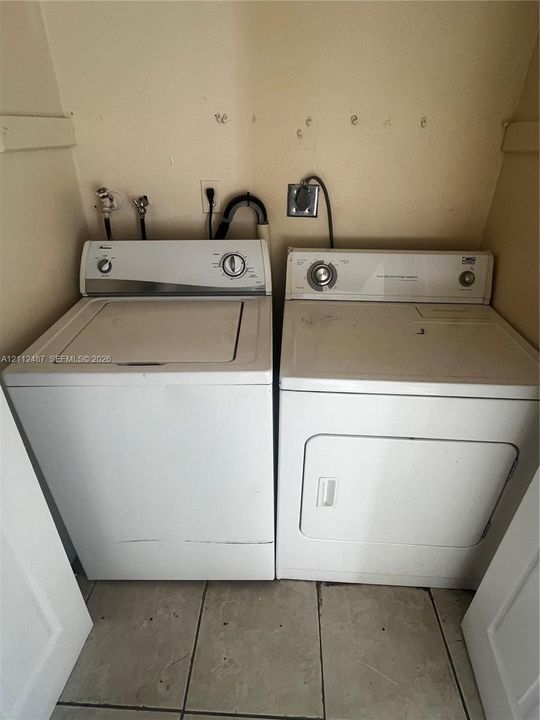 Laundry area featuring side-by-side washer and dryer units with a tiled floor