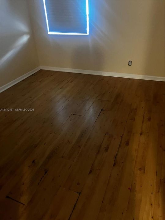 Wood-finish flooring and a window featuring a roller shade