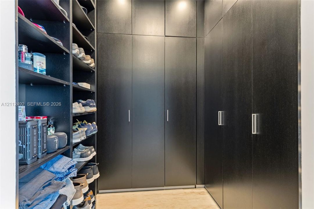 Custom black cabinetry featuring floor-to-ceiling storage, sleek metallic hardware, and integrated open shelving